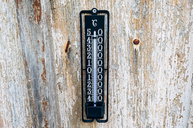 Thermostat on a wooden surface indicating itis 10 degrees celsius or 50 degrees Fahrenheit