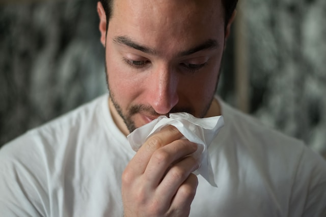 Man holding a white tissue after sneezing